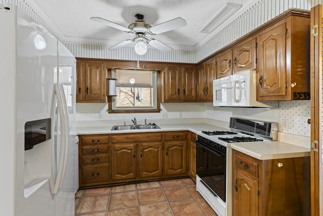 kitchen featuring a ceiling fan, a sink, white appliances, brown cabinetry, and light countertops