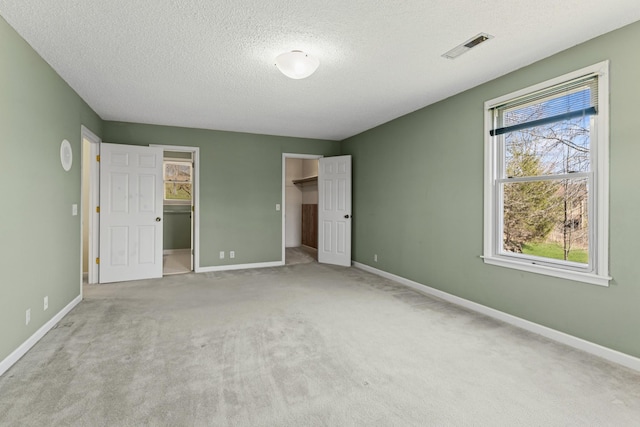 unfurnished bedroom featuring a spacious closet, baseboards, visible vents, and carpet floors
