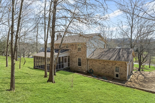 rear view of house featuring brick siding, a shingled roof, a lawn, and a sunroom