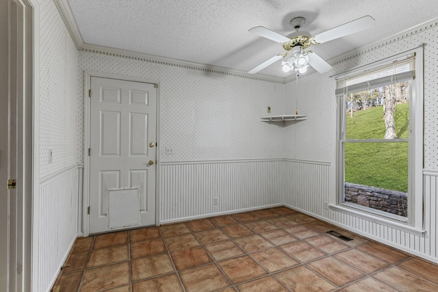 empty room featuring visible vents, a textured ceiling, a wainscoted wall, and wallpapered walls