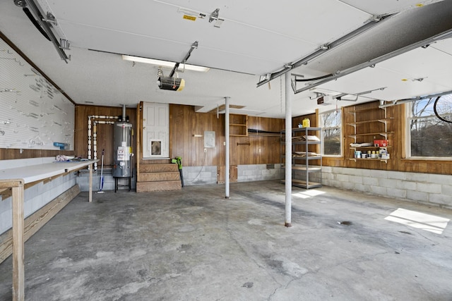 garage with gas water heater, concrete block wall, a garage door opener, and wood walls