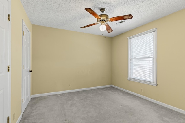 carpeted spare room featuring visible vents, baseboards, a textured ceiling, and ceiling fan