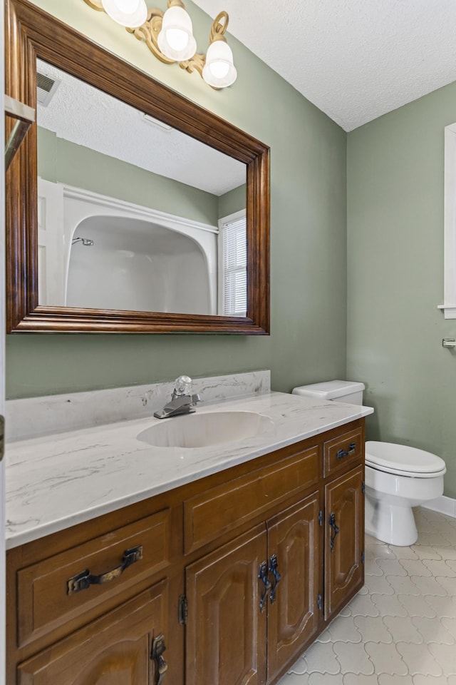 bathroom featuring toilet, vanity, and a textured ceiling