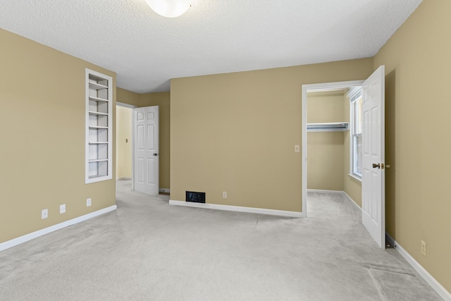 unfurnished bedroom featuring baseboards, a spacious closet, a closet, a textured ceiling, and carpet flooring