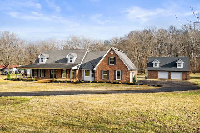 view of front of house featuring an outbuilding, a front lawn, a detached garage, covered porch, and brick siding