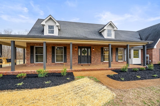 view of front of property featuring brick siding, a porch, and a shingled roof