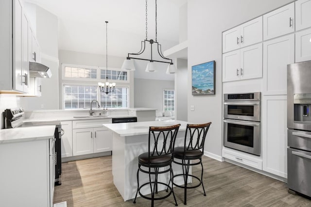 kitchen featuring a breakfast bar area, stainless steel appliances, light countertops, and a sink