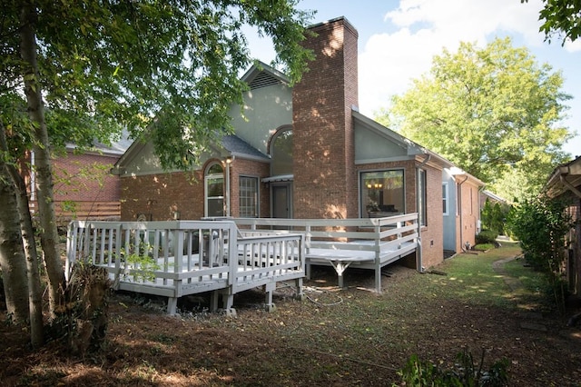 back of house featuring a wooden deck, brick siding, and a chimney