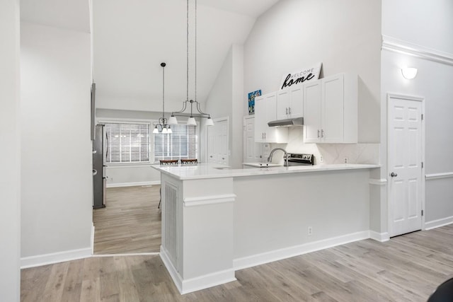 kitchen featuring high vaulted ceiling, a peninsula, light countertops, white cabinetry, and light wood-type flooring