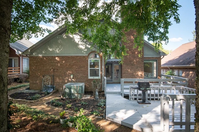 rear view of house with a wooden deck, brick siding, and cooling unit