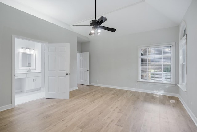 unfurnished bedroom with light wood-type flooring, baseboards, lofted ceiling, and connected bathroom