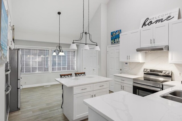 kitchen with under cabinet range hood, stainless steel appliances, and white cabinets