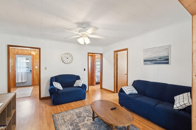 living area with baseboards, ceiling fan, crown molding, and light wood finished floors