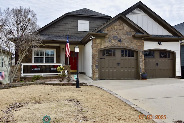 craftsman-style home featuring driveway, an attached garage, covered porch, stone siding, and board and batten siding