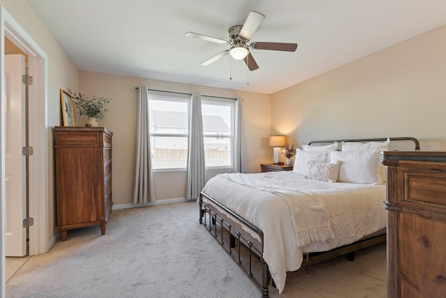 bedroom featuring baseboards, light colored carpet, and ceiling fan