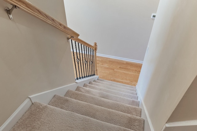 stairway with wood finished floors and baseboards