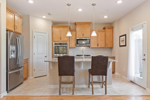 kitchen featuring visible vents, backsplash, light stone countertops, stainless steel appliances, and a kitchen island with sink