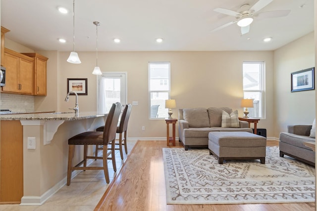 living room featuring recessed lighting, baseboards, light wood-style floors, and a ceiling fan