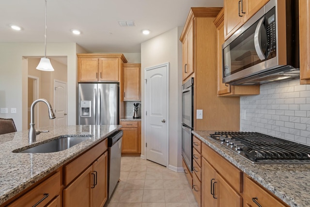 kitchen featuring visible vents, pendant lighting, a sink, appliances with stainless steel finishes, and light stone countertops