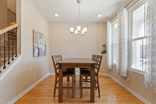 dining area featuring a healthy amount of sunlight, baseboards, a chandelier, stairs, and light wood-style flooring