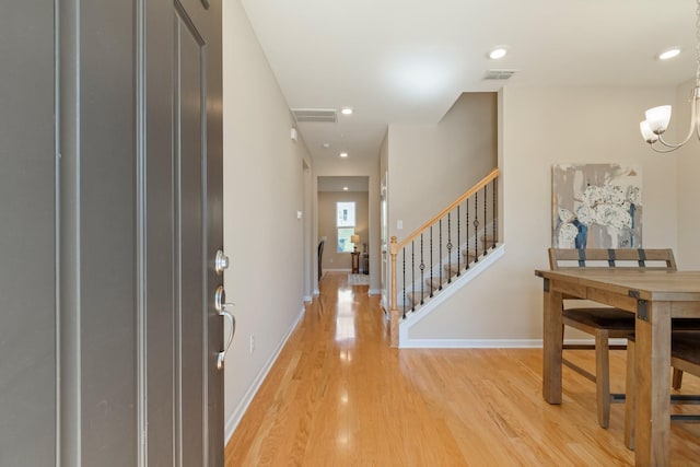 foyer featuring visible vents, baseboards, light wood-style floors, and stairs