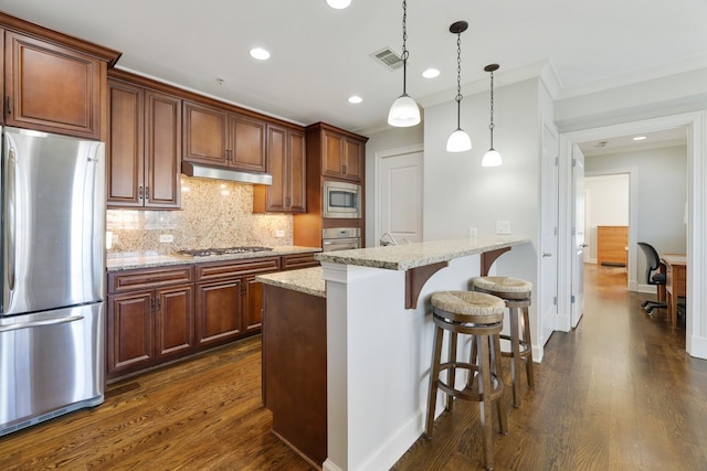 kitchen with a kitchen bar, under cabinet range hood, tasteful backsplash, dark wood finished floors, and appliances with stainless steel finishes