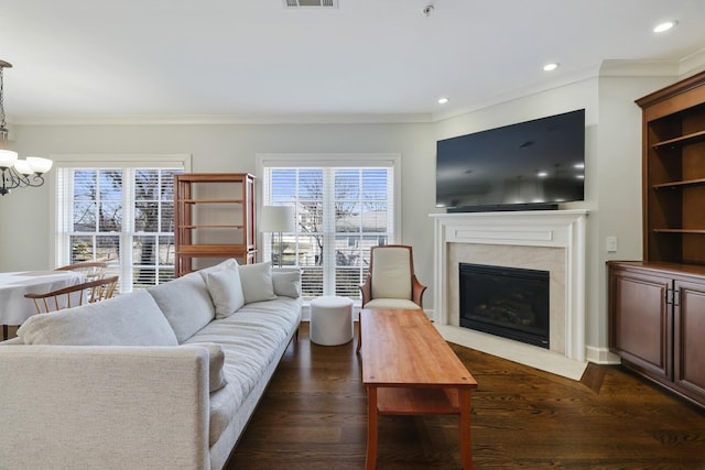 living area featuring a wealth of natural light, visible vents, dark wood-style floors, and a high end fireplace