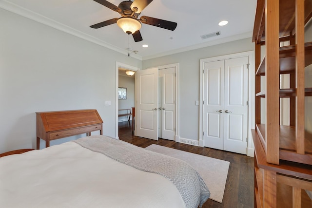 bedroom with wood finished floors, visible vents, recessed lighting, ornamental molding, and multiple closets