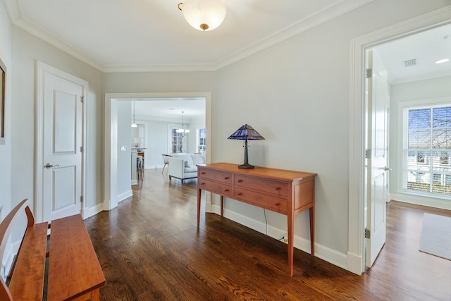 hall featuring visible vents, dark wood-type flooring, ornamental molding, baseboards, and a chandelier