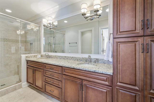 full bath featuring a sink, an inviting chandelier, a shower stall, and double vanity