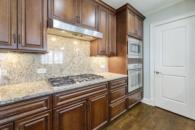 kitchen featuring dark wood-type flooring, light stone countertops, appliances with stainless steel finishes, and under cabinet range hood