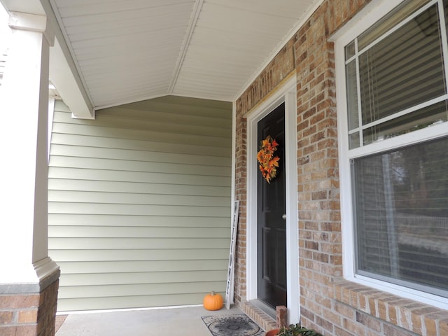 doorway to property featuring brick siding and a porch