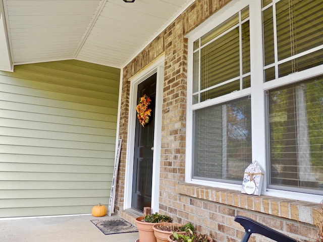 doorway to property with brick siding and covered porch