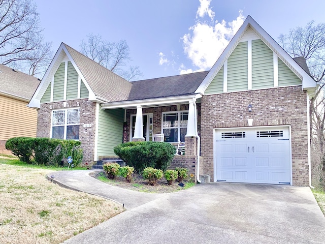 view of front of property with brick siding, a porch, roof with shingles, a garage, and driveway