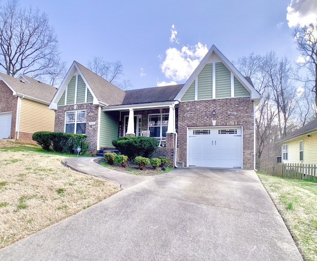 view of front of property featuring brick siding, a porch, concrete driveway, and fence