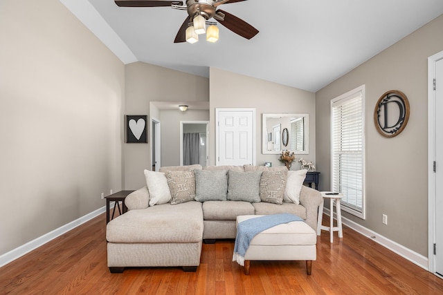 living area featuring vaulted ceiling, a ceiling fan, baseboards, and wood finished floors