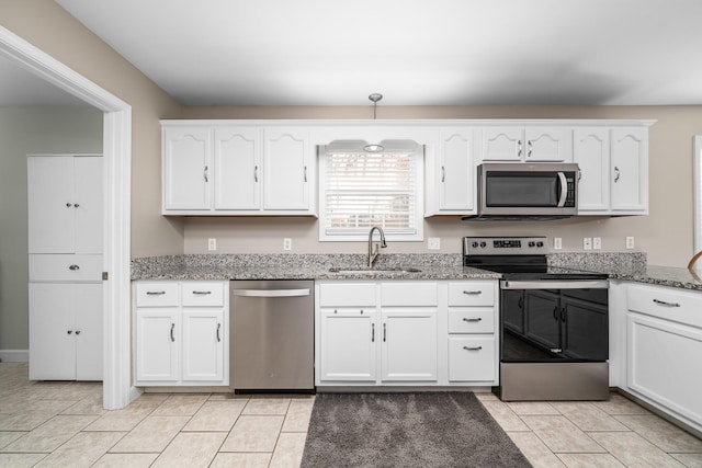 kitchen with white cabinets, light stone counters, appliances with stainless steel finishes, and a sink