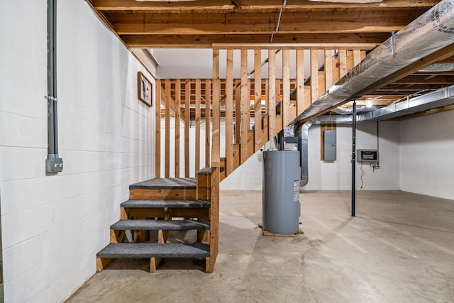 unfinished below grade area featuring electric panel, water heater, concrete block wall, and stairs