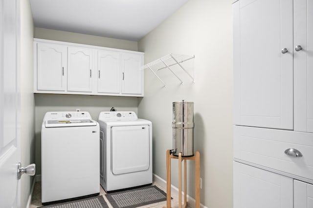 laundry room featuring baseboards, cabinet space, and separate washer and dryer