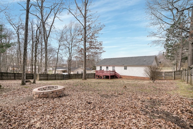 view of yard with a wooden deck, a fire pit, and a fenced backyard