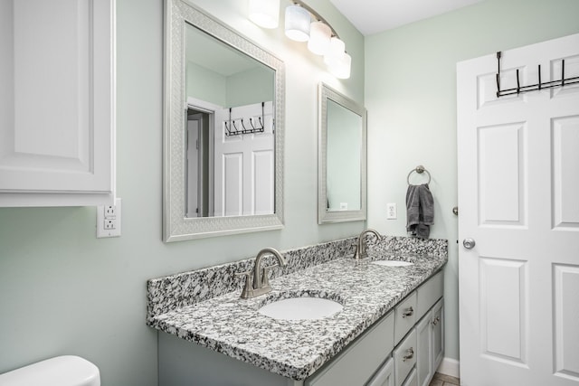 bathroom featuring double vanity, toilet, and a sink