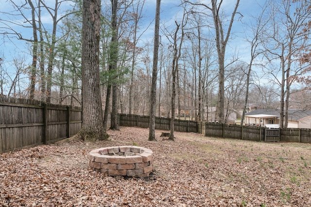 view of yard featuring a fenced backyard and a fire pit