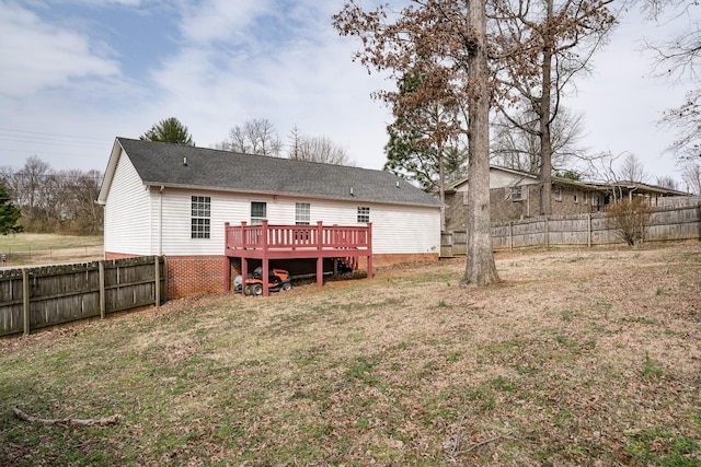 back of property featuring a fenced backyard, a lawn, a shingled roof, and a deck