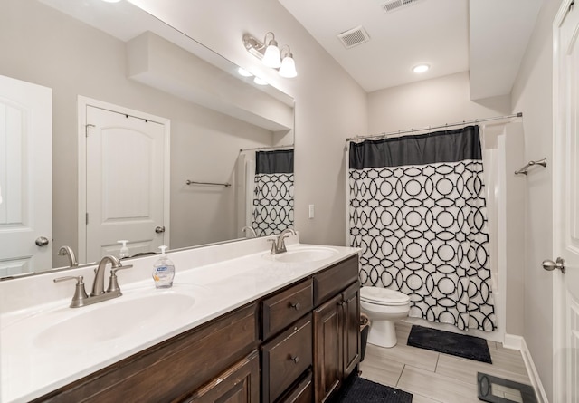 bathroom with double vanity, toilet, visible vents, and a sink