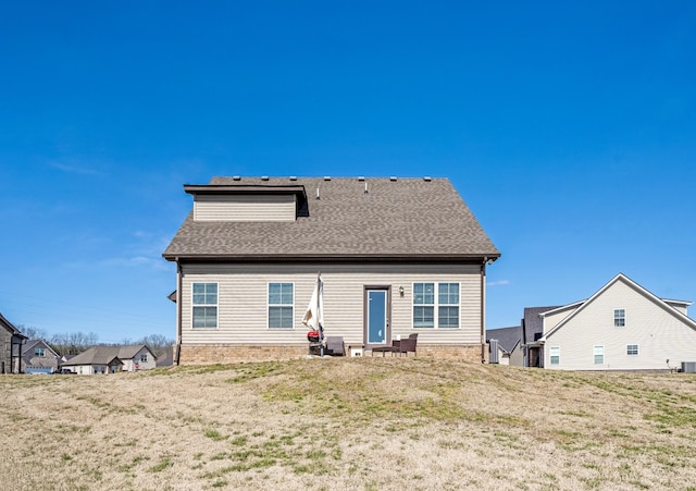 rear view of property with a lawn and a shingled roof