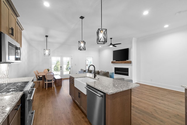 kitchen featuring a sink, dark wood-style floors, stainless steel appliances, french doors, and a fireplace