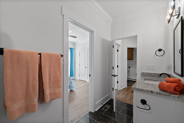 bathroom featuring toilet, wood finished floors, crown molding, baseboards, and vanity