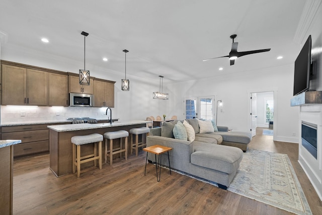 living area with a ceiling fan, dark wood-type flooring, a fireplace, and crown molding