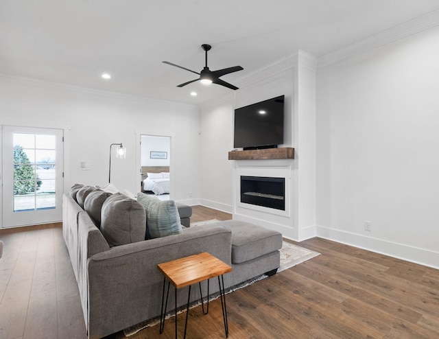 living area featuring baseboards, ornamental molding, a fireplace, and hardwood / wood-style flooring