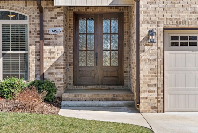 doorway to property featuring brick siding, french doors, and a garage